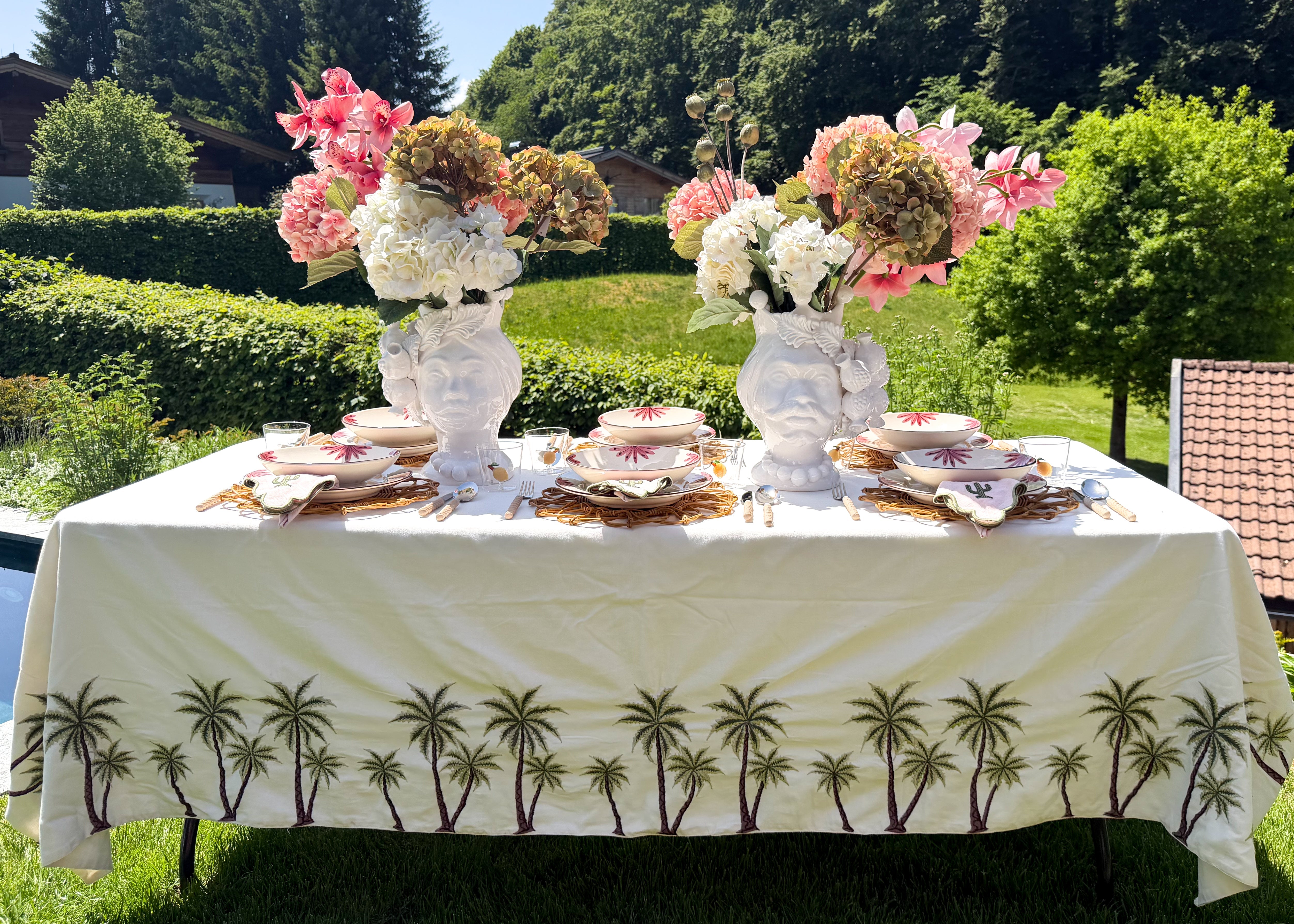 Kuratiertes Arrangement aus dekorativen Palmen-Objekten und Kerzenhaltern, die jedem Tisch eine luxuriöse und sommerliche Resort-Atmosphäre verleihen.