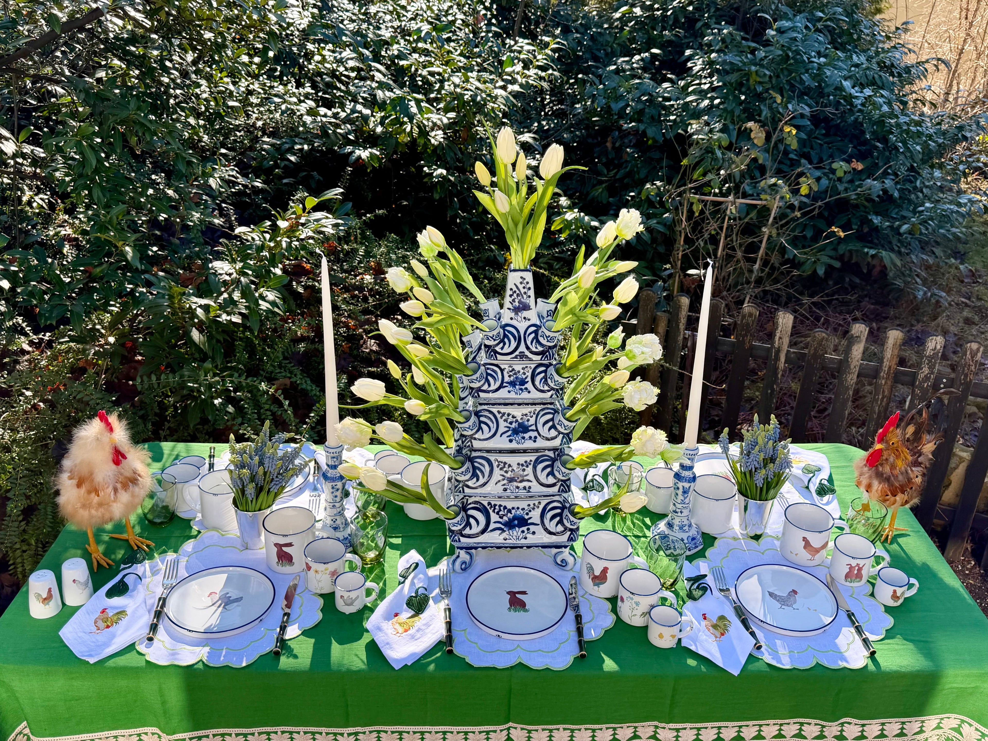 Frühlingshaft gedeckter Tisch mit blau-grünem Geschirr und handbemalten Tellern mit Hahn-Motiv von Table Desires München.